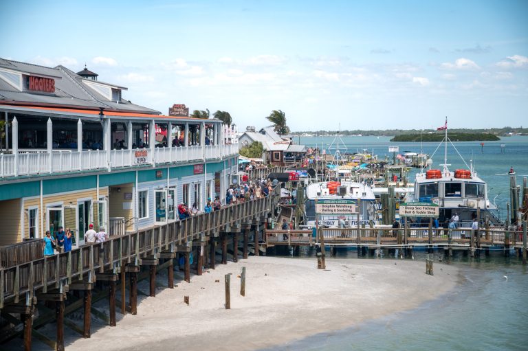 Pier with restaurants and boats docked, overlooking the ocean.