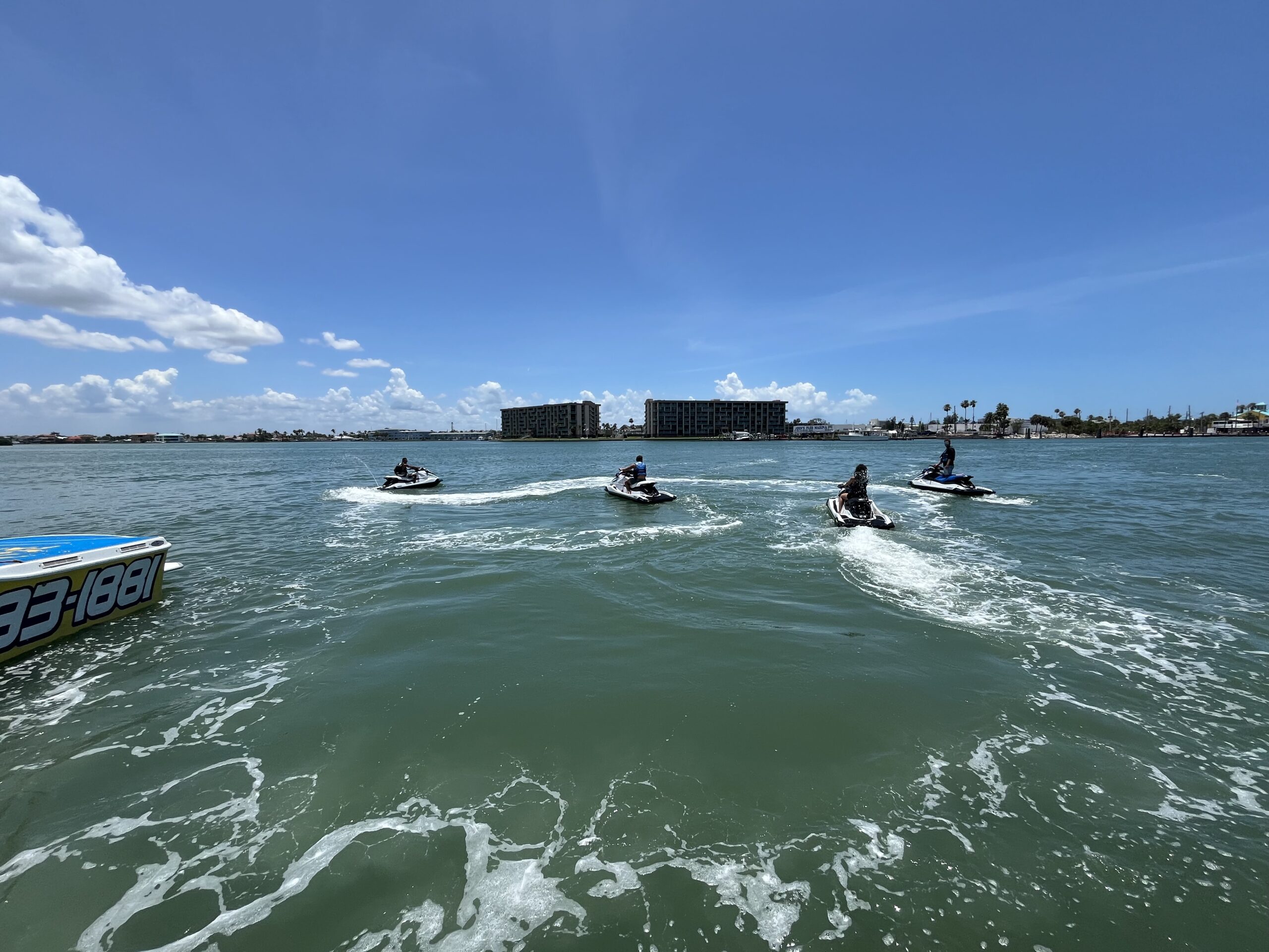 Four people riding jet skis on a sunny day in open water.